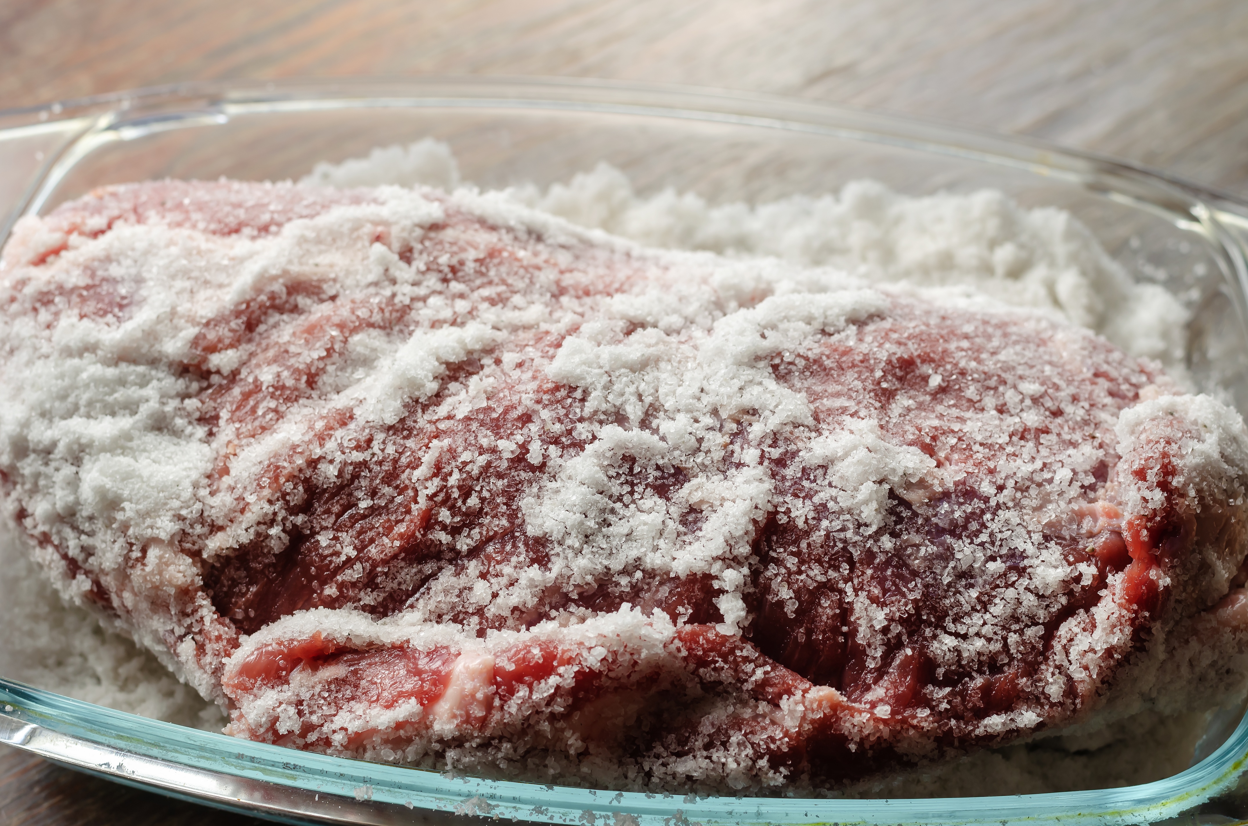 Piece of raw meat covered and ready for salt curing process