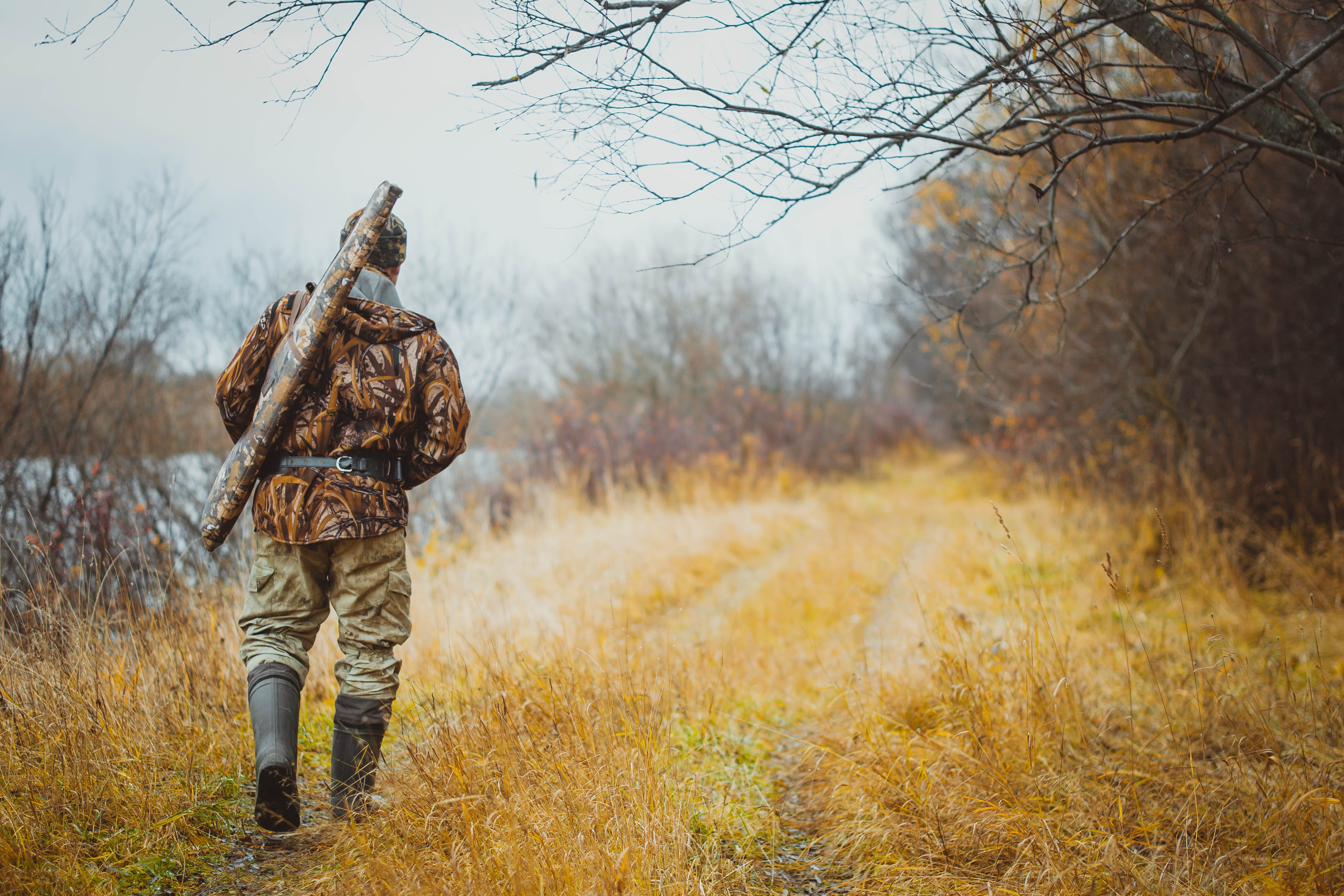 Male walking through the woods wearing camo for hunting