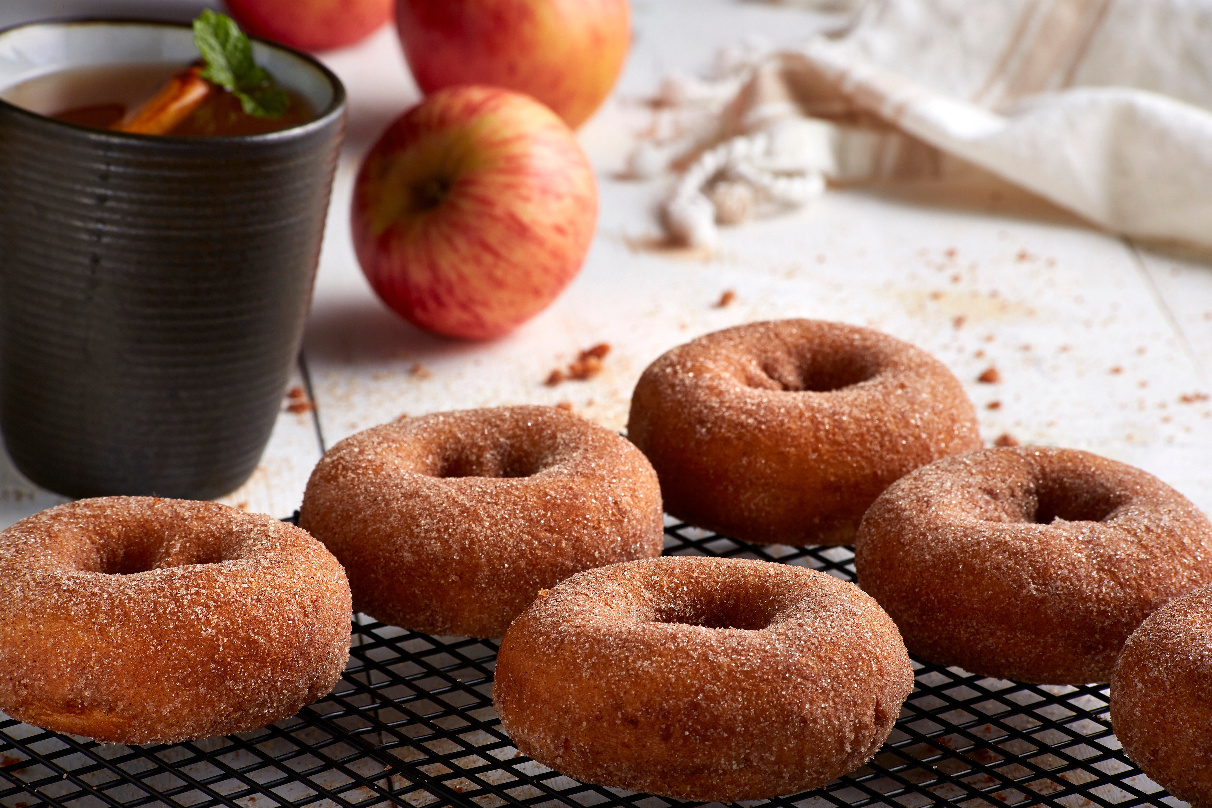 Apple cinnamon cider and donuts resting on a cooling tray