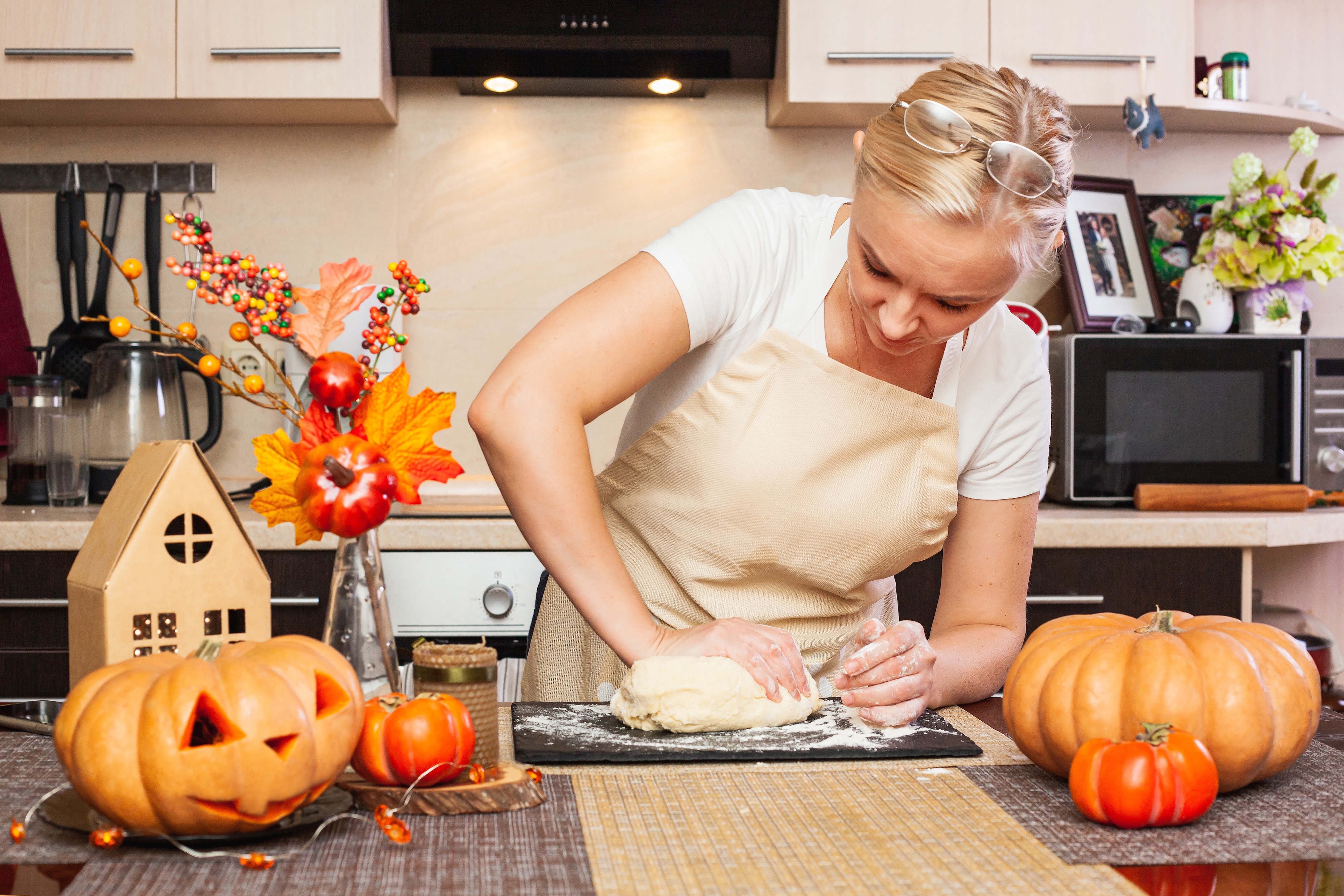 A woman in a fall-themed kitchen kneading dough for a fall baked treat