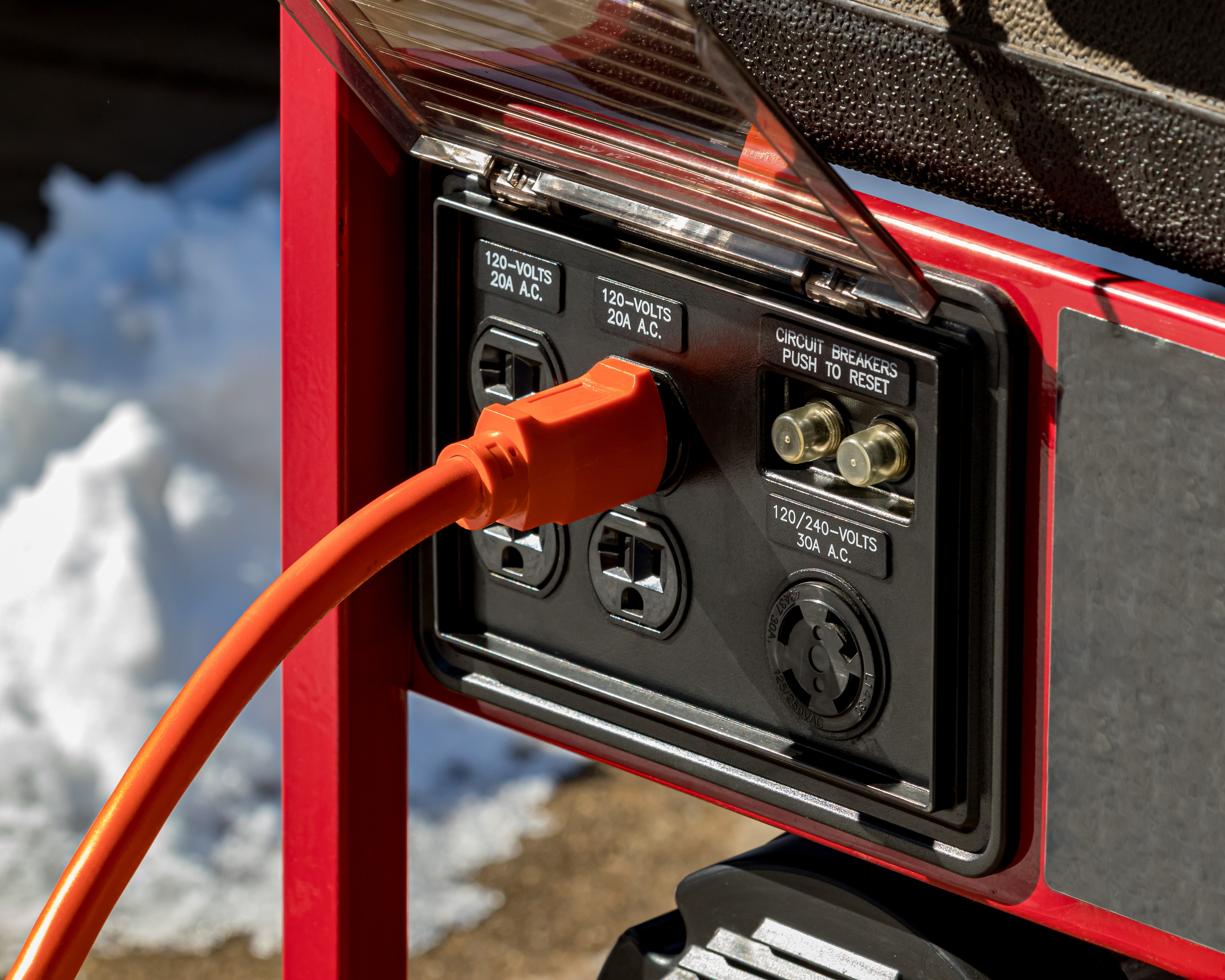 A power cord plugged into a portable generator during the winter