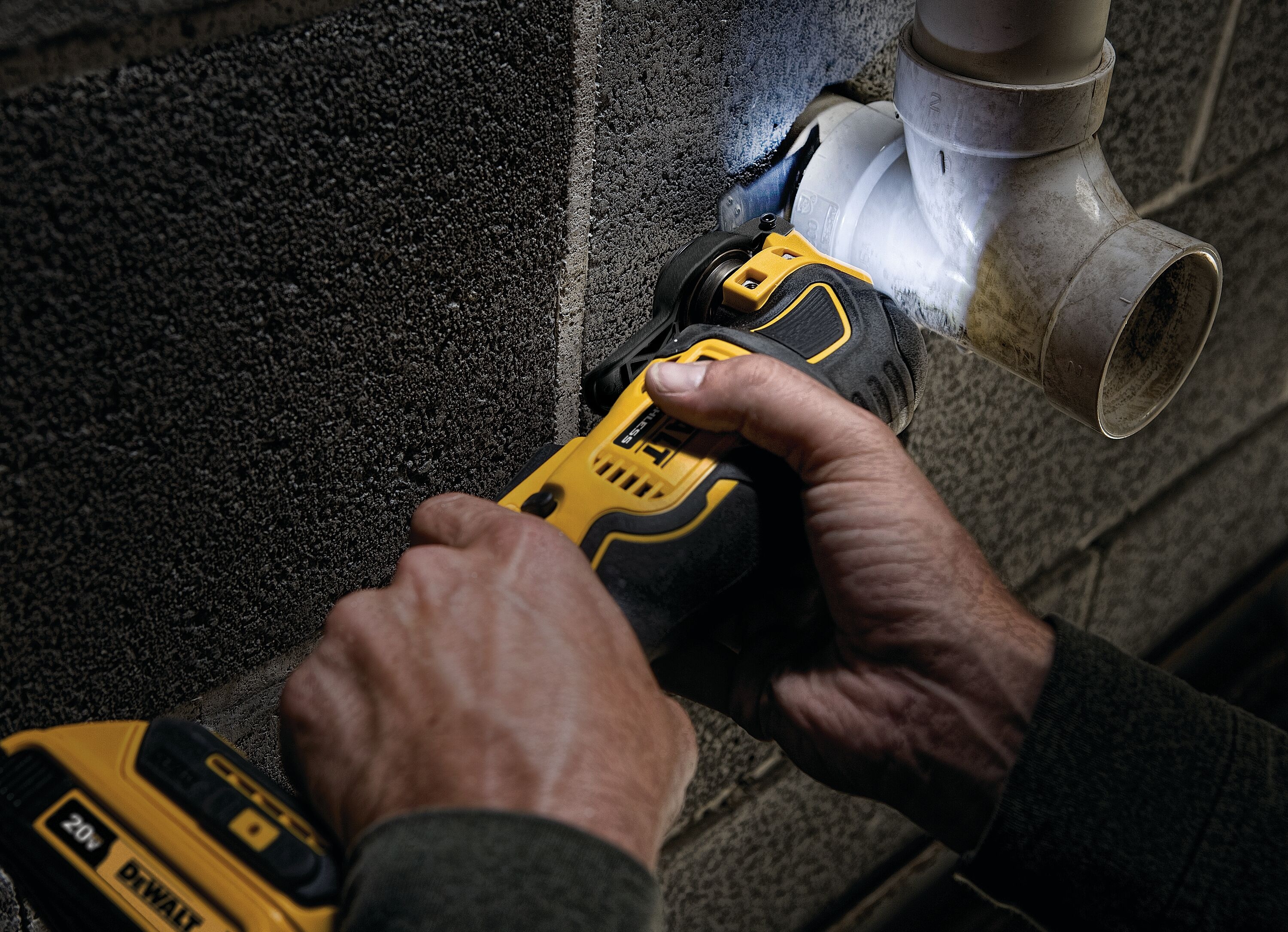 Person using a DeWalt multi-tool to work a PVC pipe