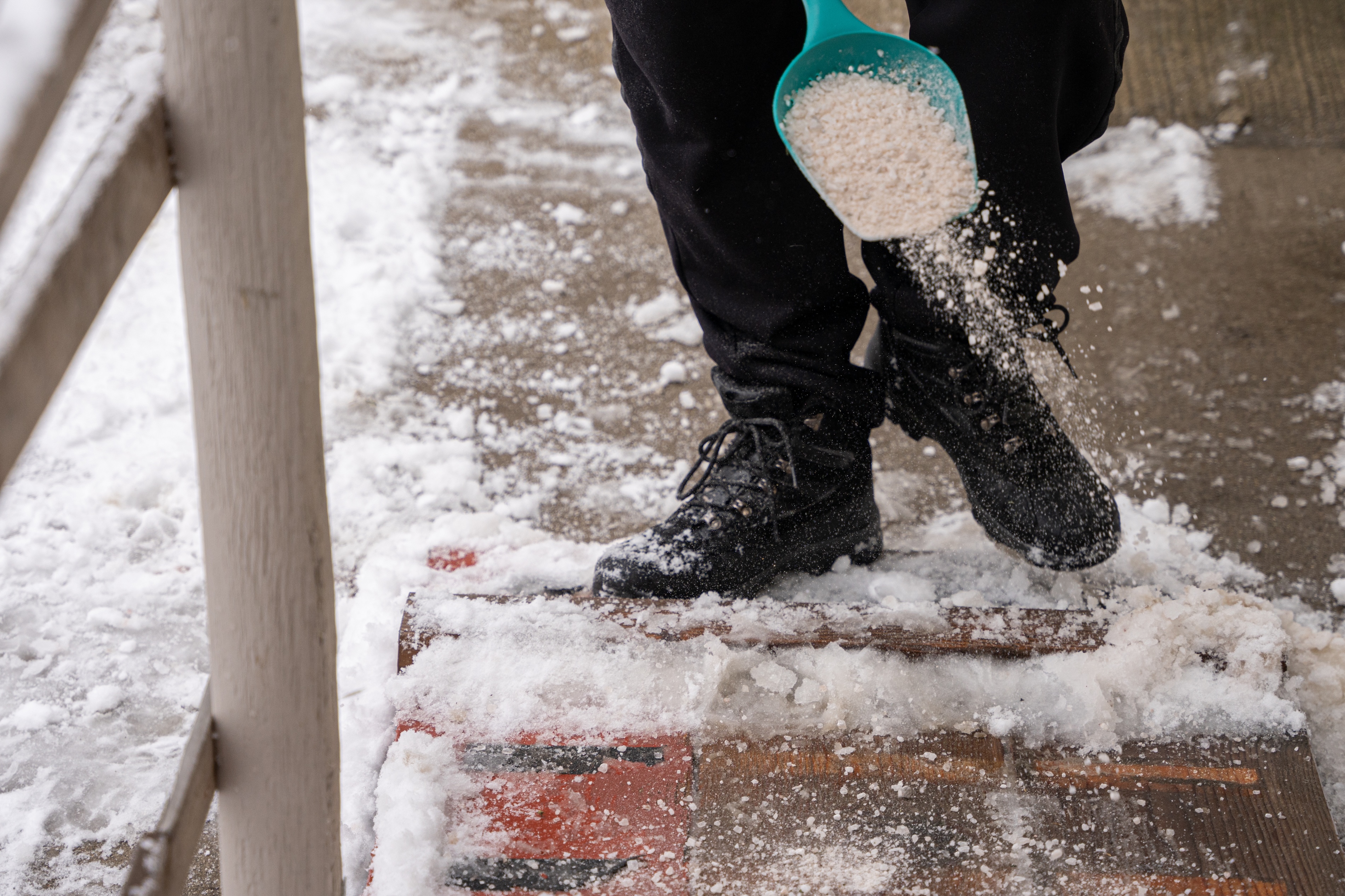 person spreading salt to remove ice