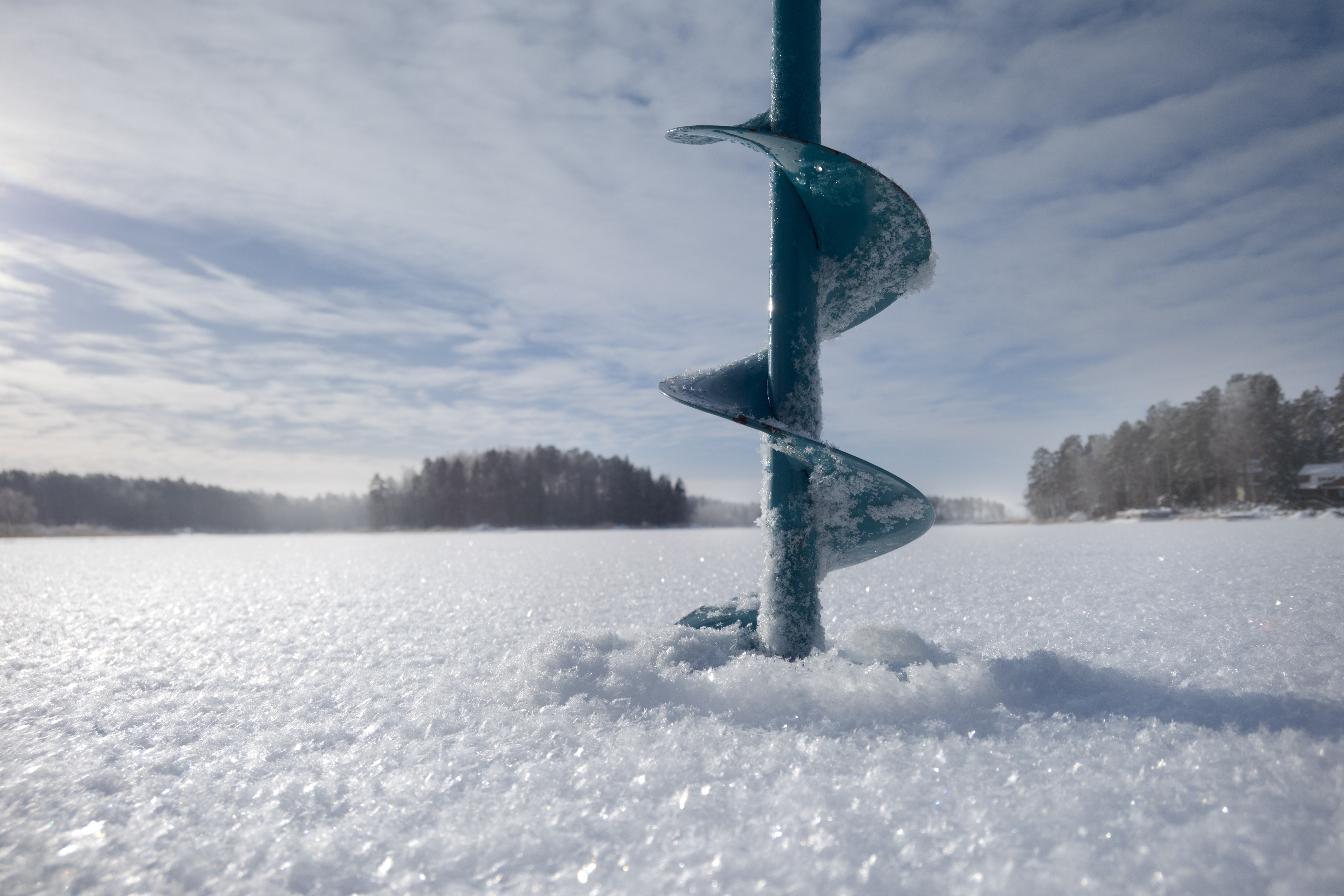 Auger drilling into ice for ice fishing