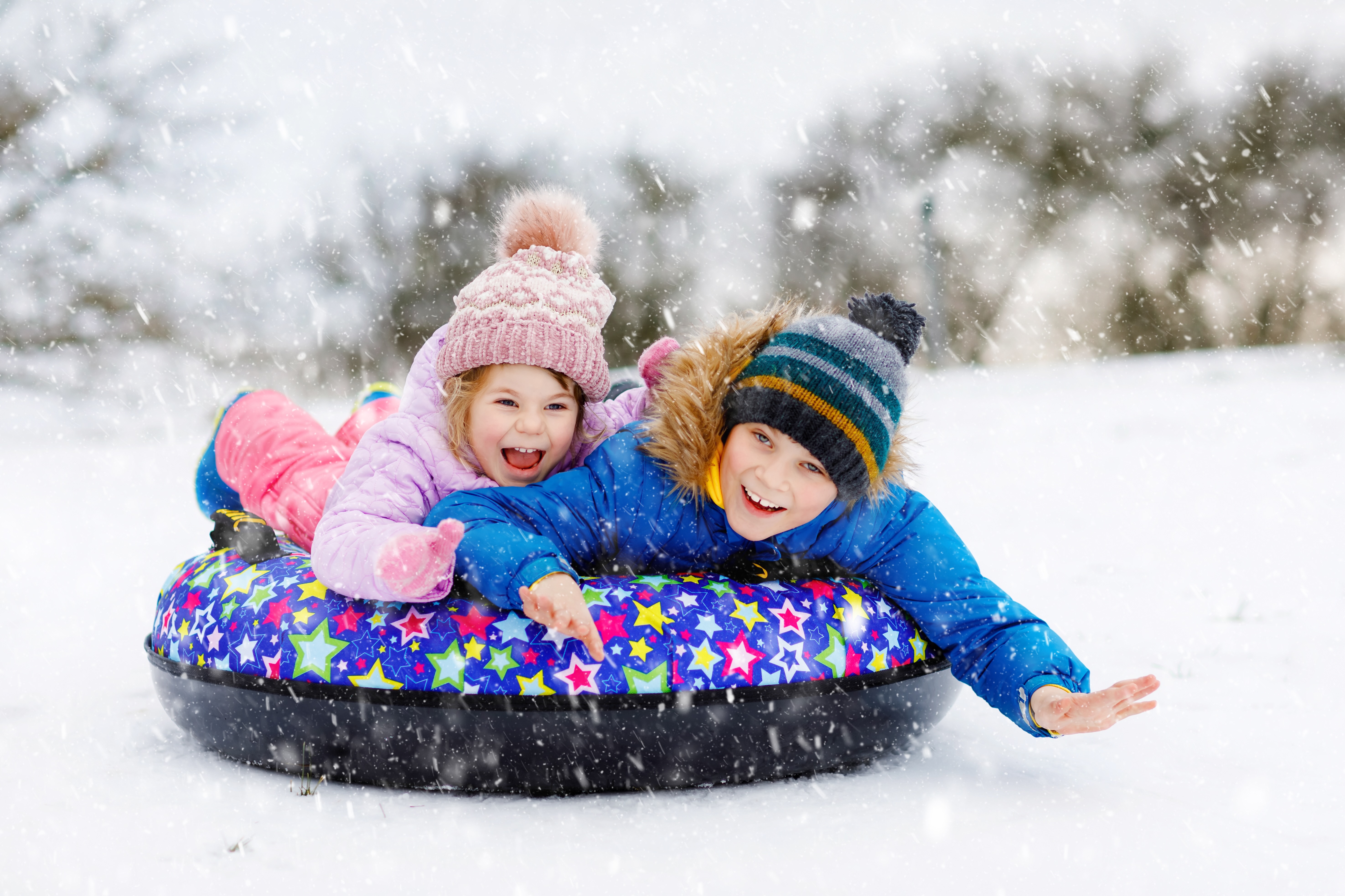 Brother and sister having fun on a snow tube sledding