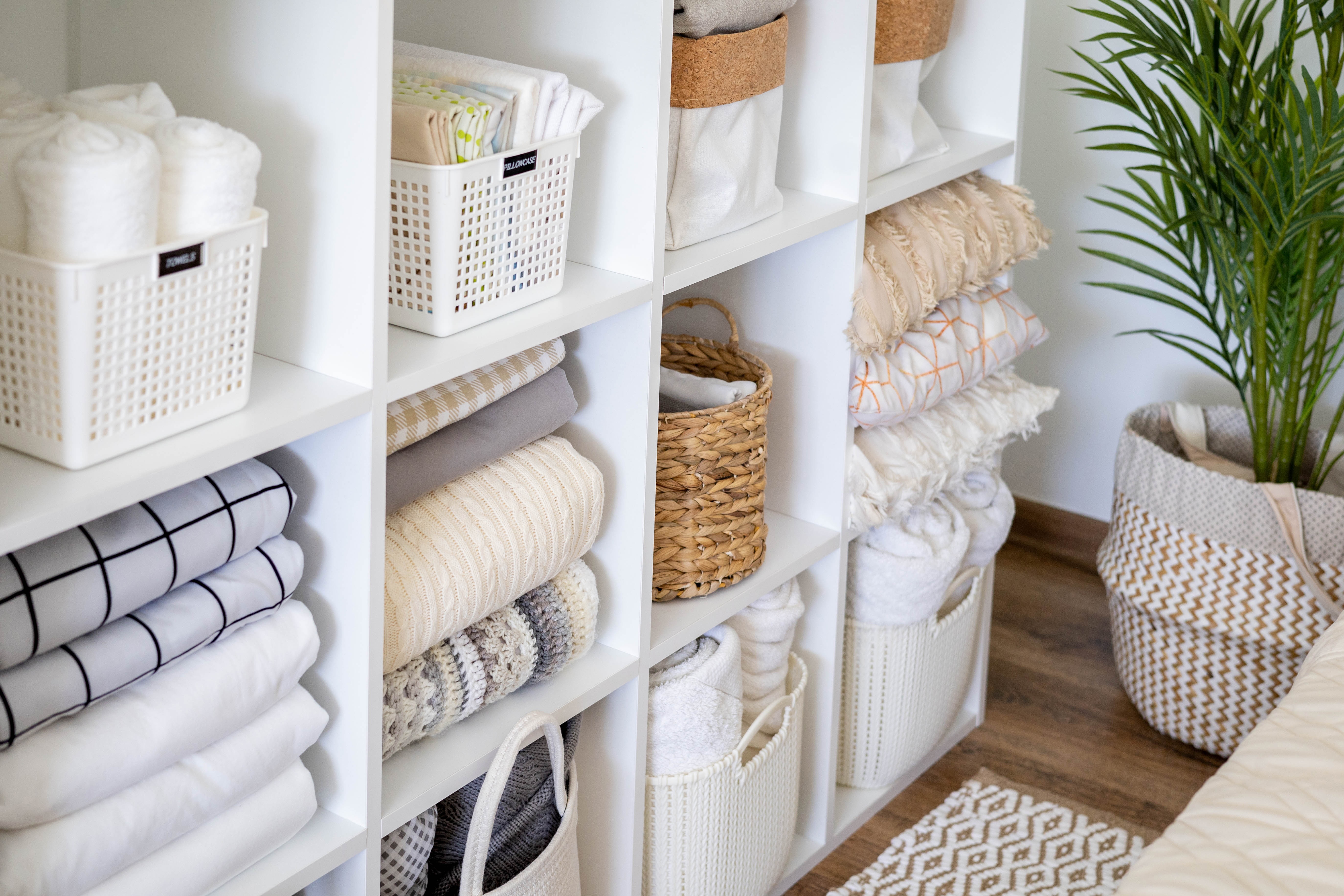 Bedroom storage area with baskets that are organizing towels, blankets, pillows
