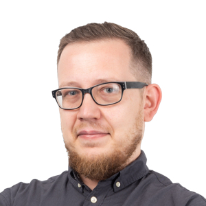 Headshot of a man with glasses and beard wearing a dark button-up shirt against a white background.
