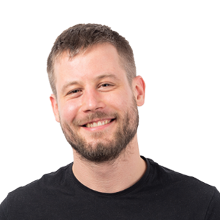 Headshot of a smiling man with short brown hair and beard wearing a black t-shirt against a white background.