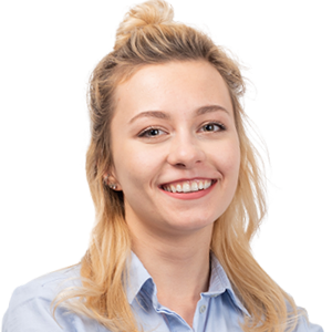 Smiling woman with blonde hair in a top bun wearing a light blue button-up shirt against a white background