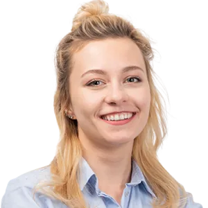 Smiling woman with blonde hair in a top bun wearing a light blue button-up shirt against a white background