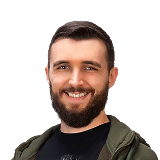 Smiling man with dark beard wearing olive green jacket over black shirt against white background