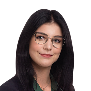 Headshot of a woman with long black hair and glasses, wearing a dark jacket over a green shirt, smiling at the camera.