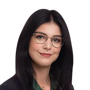 Headshot of a woman with long black hair and glasses, wearing a dark jacket over a green shirt, smiling at the camera.
