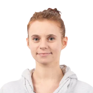 Portrait of a young girl with reddish-brown hair in a bun, wearing a light gray hoodie against a white background.