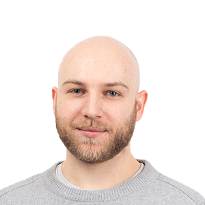 Headshot of a bald man with a beard wearing a gray sweater against a white background