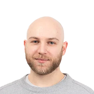 Headshot of a bald man with a beard wearing a gray sweater against a white background