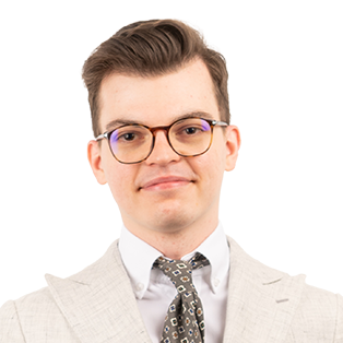 Professional headshot of a man wearing glasses, beige blazer, white shirt, and patterned tie against white background.