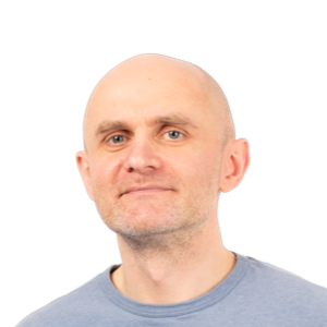Headshot of a bald man with a neutral expression wearing a light blue t-shirt against a white background.