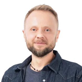 Professional headshot of a man with beard and short blonde hair wearing a dark denim shirt against white background.
