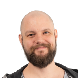 Professional headshot of a bald man with a full dark beard, wearing a black jacket over a gray shirt, smiling at the camera against a white background.