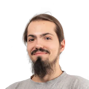 Portrait of a man with long dark hair, mustache and goatee, wearing a gray t-shirt against a white background.