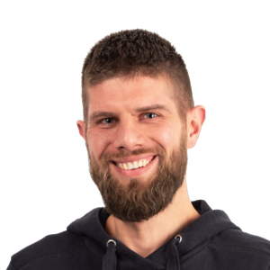 Headshot of a smiling man with a beard wearing a black hoodie against a white background.