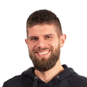 Headshot of a smiling man with a beard wearing a black hoodie against a white background.