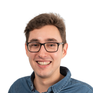 Smiling man with glasses wearing a blue denim shirt against a white background