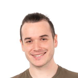Portrait of a smiling young man with dark hair wearing a brown shirt against a white background.