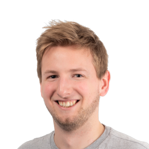 Headshot of a smiling young man with light brown hair wearing a gray t-shirt against a white background.