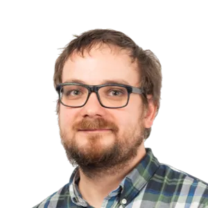 Headshot of a man with glasses and beard wearing a plaid shirt against a white background.