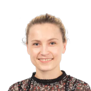 Smiling woman with blonde hair pulled back, wearing a dark patterned top against a white background.