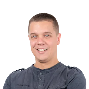 Headshot of a smiling young man with short brown hair wearing a dark blue henley shirt against a white background.
