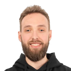 Headshot of a smiling man with a beard wearing a black hoodie against a white background.