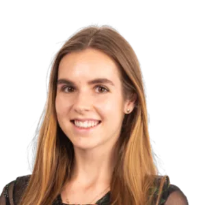 Professional headshot of a smiling woman with long reddish-brown hair wearing a dark colored top against a white background.