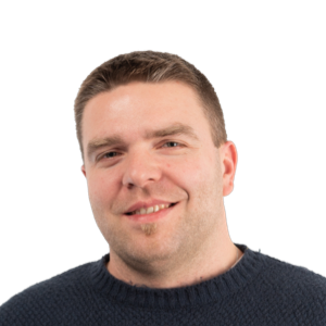 Headshot of a smiling man with short brown hair wearing a dark sweater against a white background.