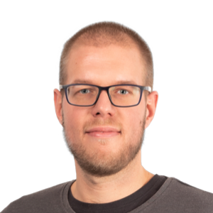 Headshot of a man with short light brown hair, glasses, and a beard wearing a dark t-shirt against a white background.