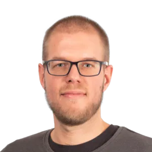 Headshot of a man with short light brown hair, glasses, and a beard wearing a dark t-shirt against a white background.