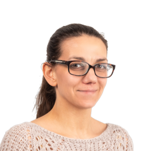 Woman wearing glasses and a beige knit sweater, smiling at the camera against a white background