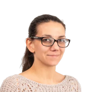 Woman wearing glasses and a beige knit sweater, smiling at the camera against a white background