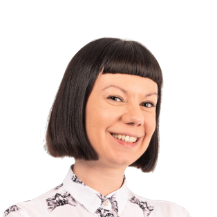 Woman with short dark bob haircut and bangs, wearing a white floral patterned shirt, smiling at camera against white background.