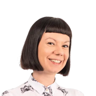 Woman with short dark bob haircut and bangs, wearing a white floral patterned shirt, smiling at camera against white background.