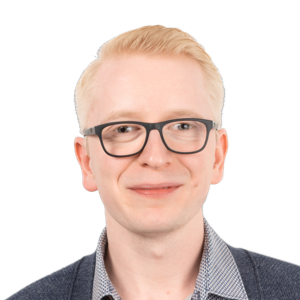 Headshot of a young man with blonde hair and glasses wearing a checkered shirt and dark sweater against a white background.