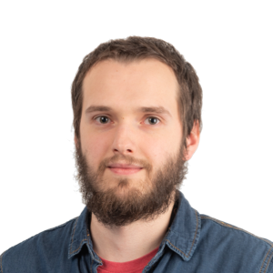 Headshot of a bearded man with short brown hair wearing a denim shirt over a red shirt against a white background.