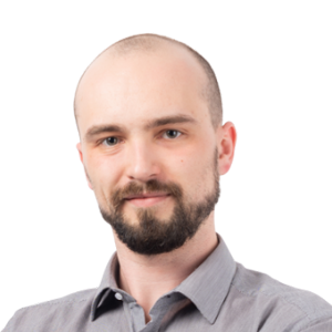 Headshot of a man with a beard wearing a gray button-up shirt against a white background.
