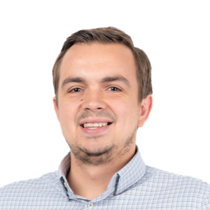 Professional headshot of a smiling man with brown hair wearing a light blue checkered shirt against a white background.
