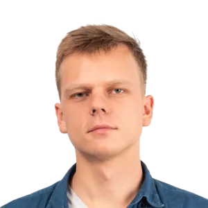 Headshot of a young man with light brown hair wearing a dark blue button-up shirt over a white undershirt against a white background.