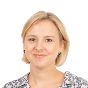Blonde woman with short hair wearing a patterned top and dark earrings, smiling at camera against white background