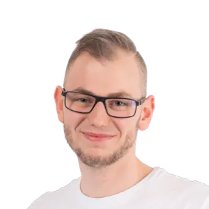 Portrait of a young man with short hair, glasses, and a light beard wearing a white t-shirt against a white background.