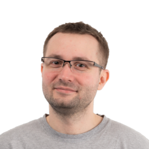Headshot of a man with short brown hair and glasses wearing a gray t-shirt against a white background.